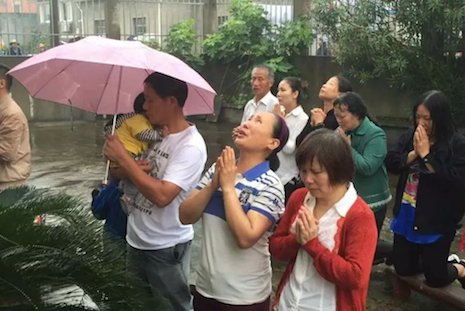 <p>Catholics kneel and pray outside the Jingjiang church as they witness the removal of their cross. (Photo supplied)</p>