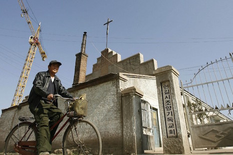 <p>A man cycles past a Korean church in Yanji in Yanbian on the China-North Korea border in this file photo. For North Korean refugees, Christian aid groups are crucial in providing shelter and aid. (Photo by Peter Parks/AFP)</p>