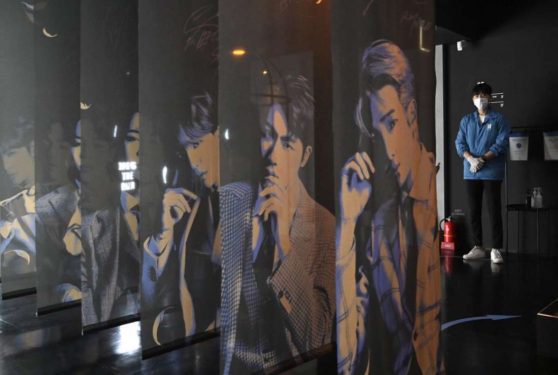 A staff member stands next to banners showing portraits of South Korean K-pop boy band BTS members at a BTS pop-up store in Seoul on Nov. 19, 2020