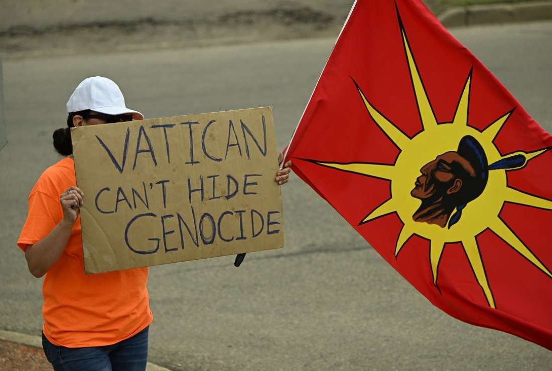 A protester holds a sign as Pope Francis arrives in Edmonton, Canada, on July 24 for a five-day official visit