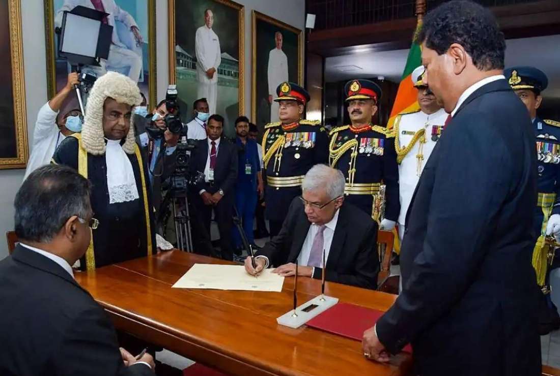 This handout photo taken on July 21 and released by Sri Lanka's parliament shows president-elect Ranil Wickremesinghe, center, signing documents during his swearing-in ceremony as Sri Lanka's President, at the parliament in Colombo