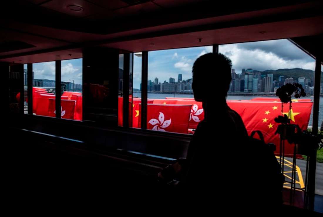 A man walks past Hong Kong and Chinese flags in Hong Kong on June 29, ahead of the 26th anniversary of the city’s handover from Britain to China on July 1