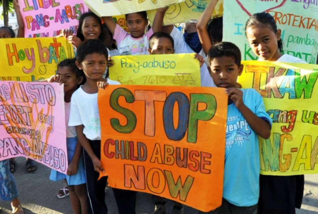 In this file photo, children from the depressed area of Baseco in Manila carry signs calling for the end of child abuse, in a parade marking United Nations Children's Month on Oct. 17, 2008.