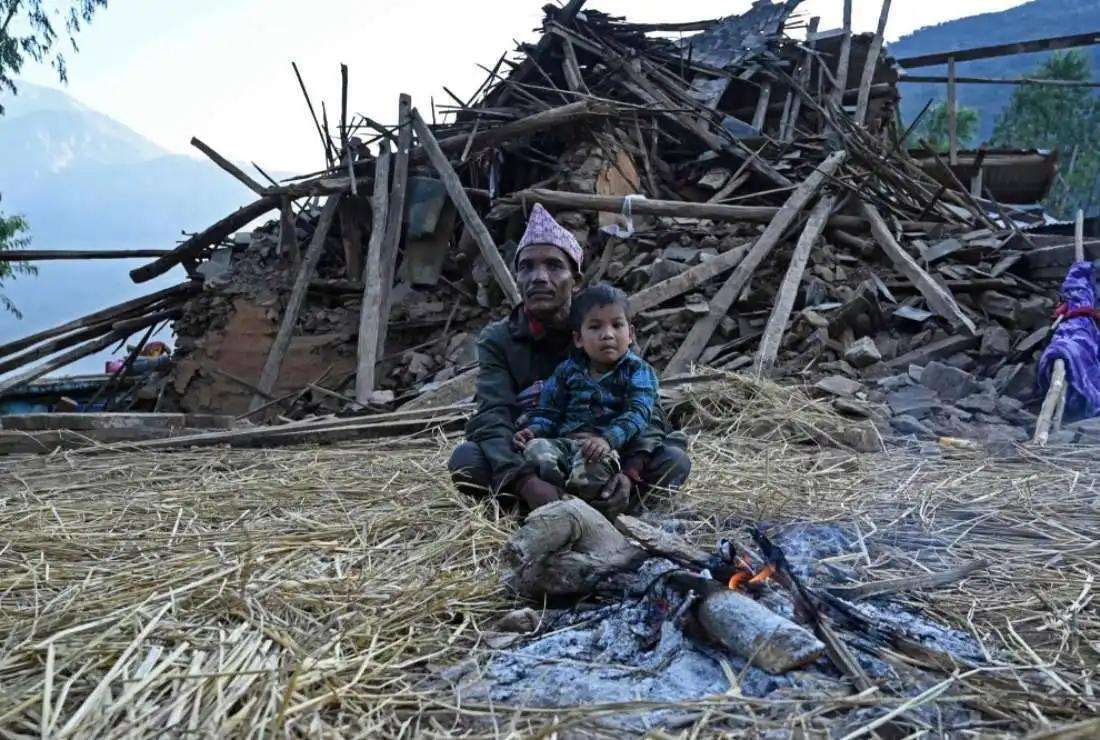 Survivors of a recent earthquake sit in front of a damaged house in Chiuri, a village in Nepal's Jajarkot district on Nov. 5